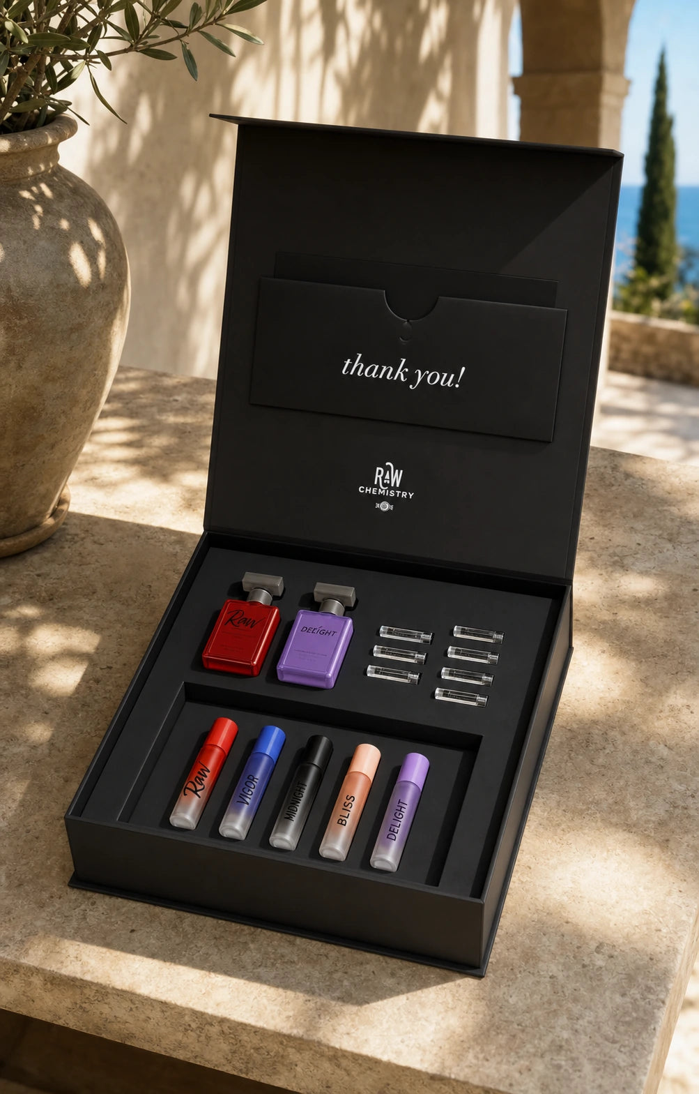 Open RawChemistry Discovery Collection on sunlit limestone, with two mini sprays, seven sample vials, and five labeled roll-ons